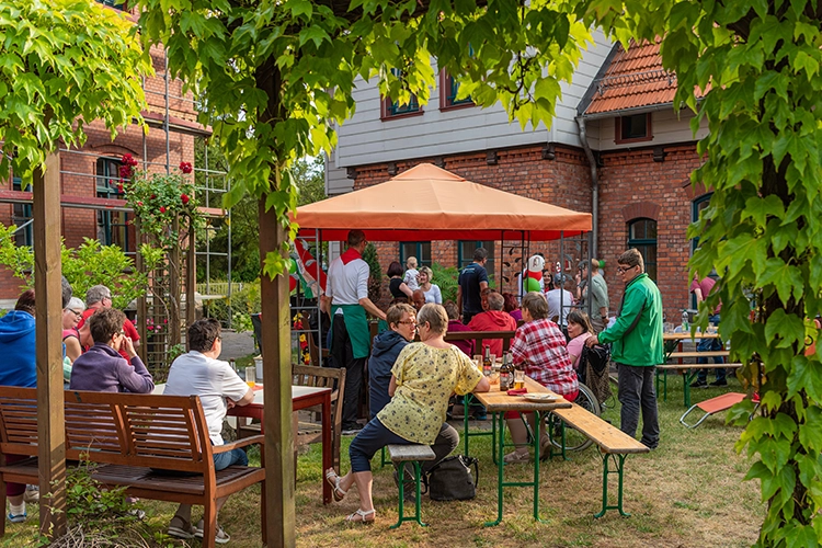 Bewohner sitzen gemeinsam im Garten unter Pavillon und essen
