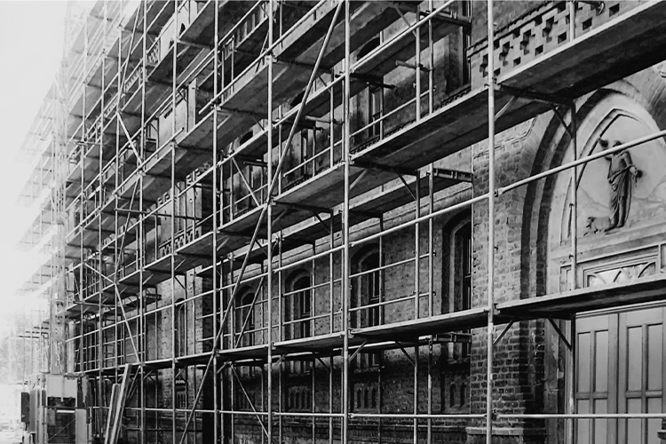 Schwarz-weiß-Foto eines historischen Backsteingebäudes mit Baugerüst