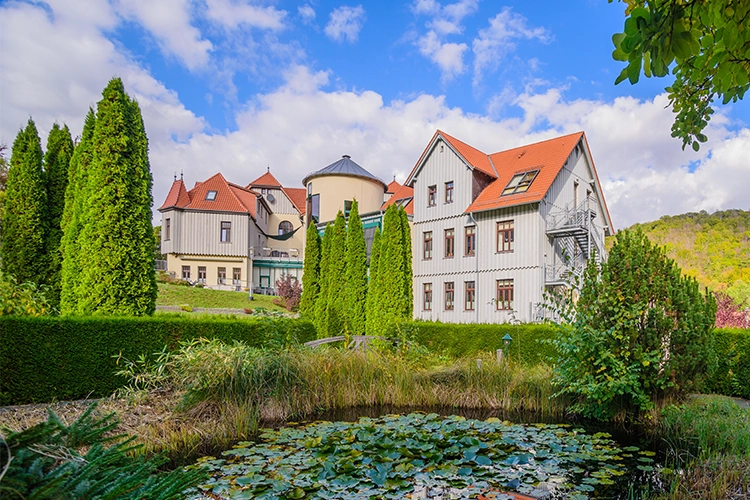 Wohnanlage mit mehreren Gebäuden und Teich im Garten