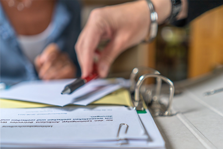 Hand zeigt auf Unterlagen während eines Beratungsgesprächs