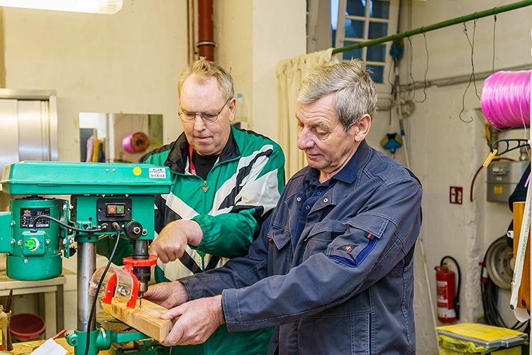 Zwei Männer arbeiten gemeinsam an einer Maschine in einer Werkstatt