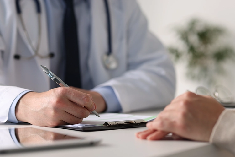 Arzt notiert Informationen während eines Gesprächs mit einem Patienten