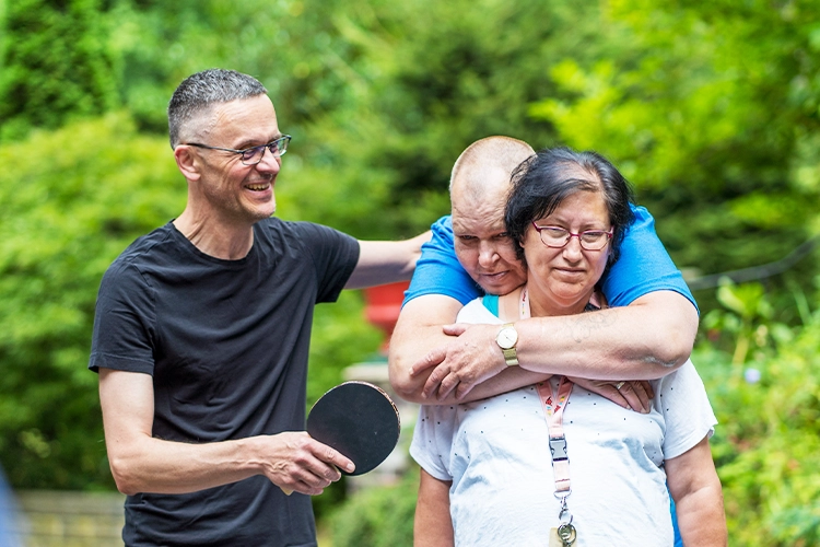 Betreuungssituation im Freien mit drei Personen und Ballspiel