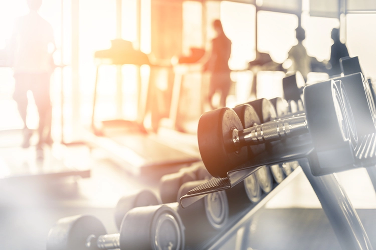 Hanteln im Fitnessraum mit verschwommenen Personen im Hintergrund
