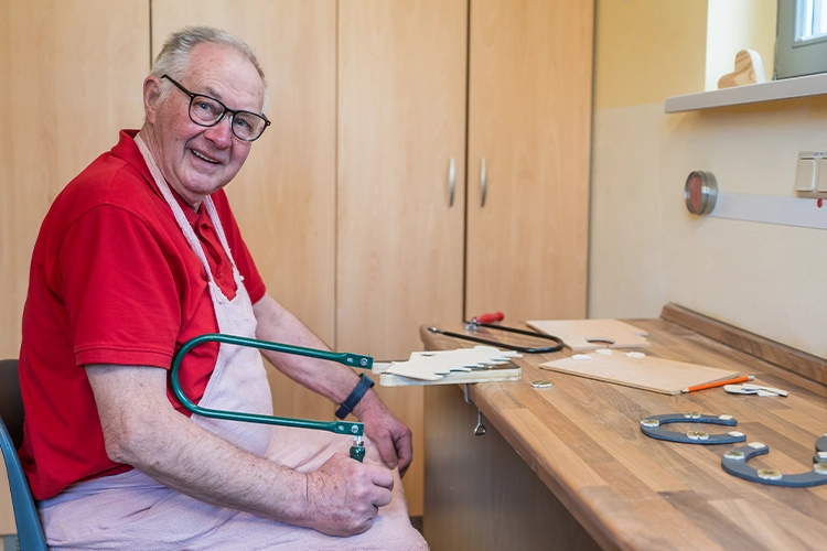 Älterer Mann arbeitet mit Werkzeug an Holz