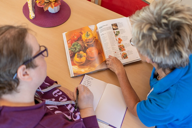 Zwei Personen planen Mahlzeiten mit Kochbuch