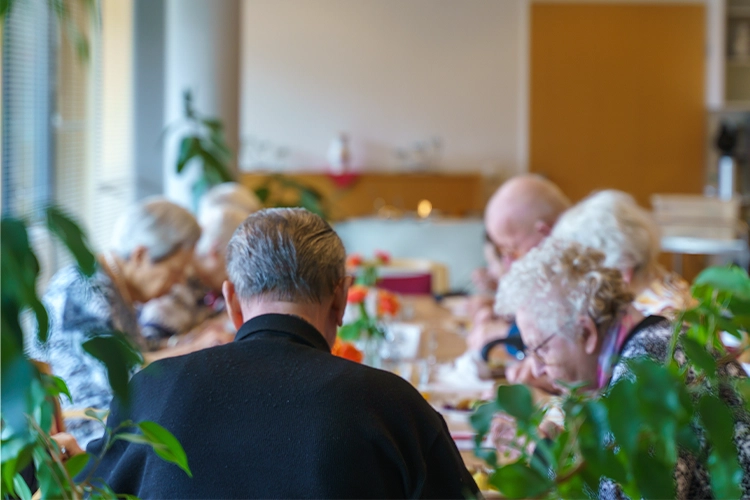 Senioren sitzen gemeinsam am Tisch beim Essen