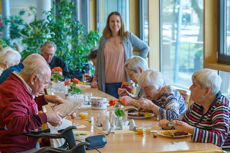 Gruppe von Senioren beim gemeinsamen Mittagessen mit Gastgeberin
