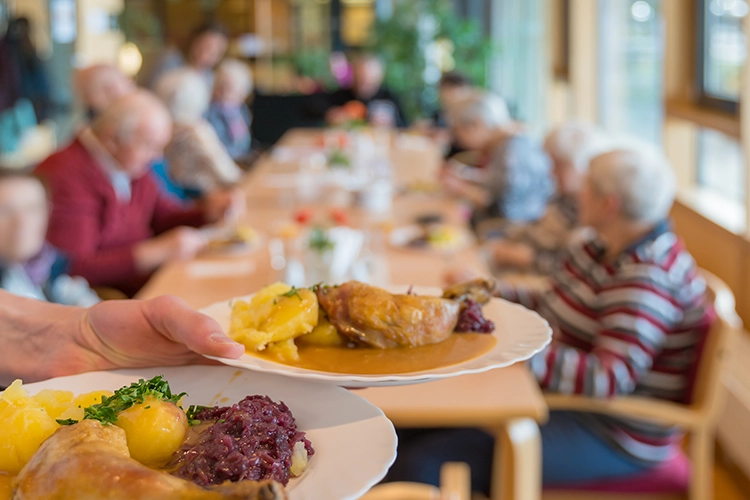 Serviertes Mittagessen auf Teller in Gemeinschaftsraum mit Senioren