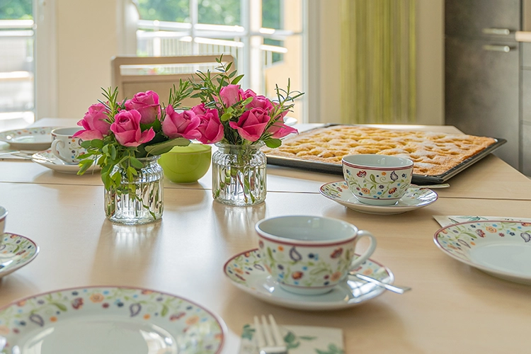 Gedeckter Tisch mit Kaffee, Blumen und Kuchen