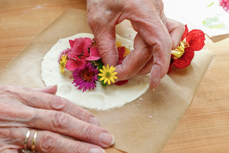 Hände dekorieren Salzteig mit bunten Blumen