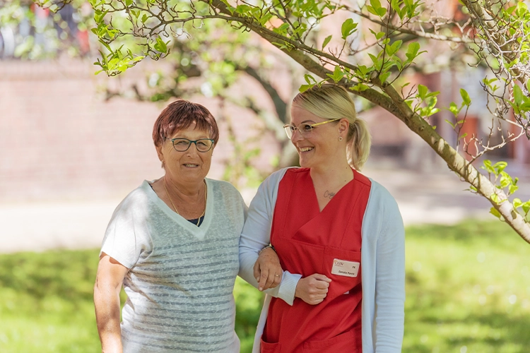 Spaziergang mit Seniorin und Pflegekraft im Garten
