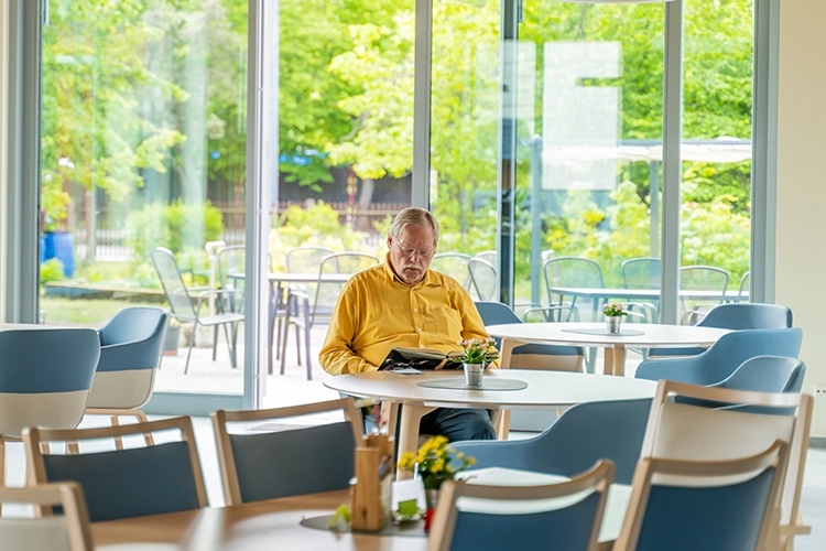 Mann sitzt allein im Aufenthaltsraum und liest ein Buch