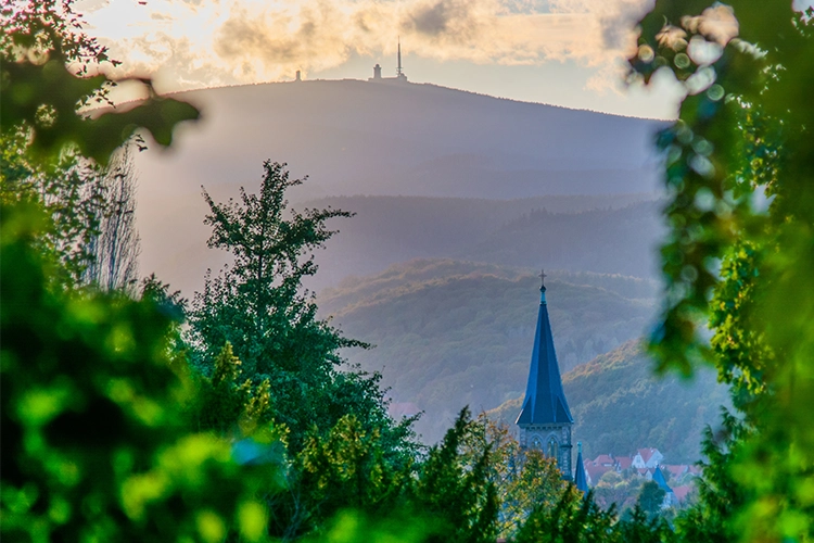 Blick auf Kirche und Brocken durch grüne Landschaft