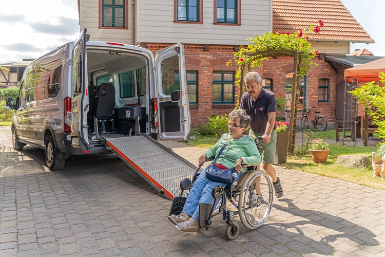 Rollstuhlfahrer wird in Transporter geschoben