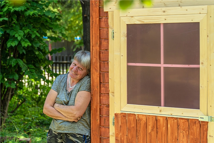 Frau lehnt entspannt an Gartenhäuschen