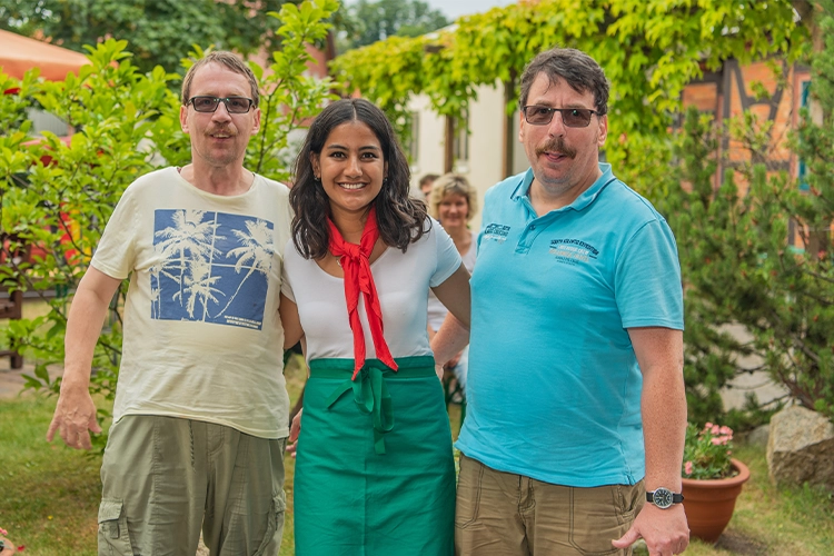Drei Personen lächeln gemeinsam in die Kamera