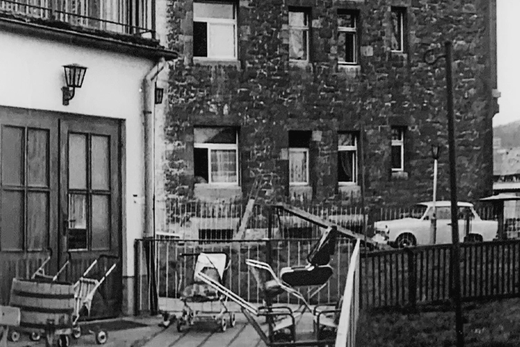Alter Hinterhof mit Kinderwagen vor Wohnhaus (Schwarzweiß)