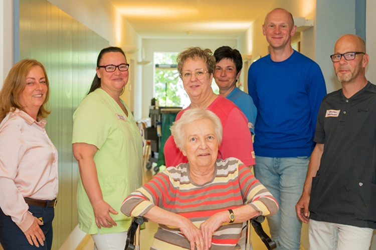Pflegeteam steht mit Bewohnerin im Flur