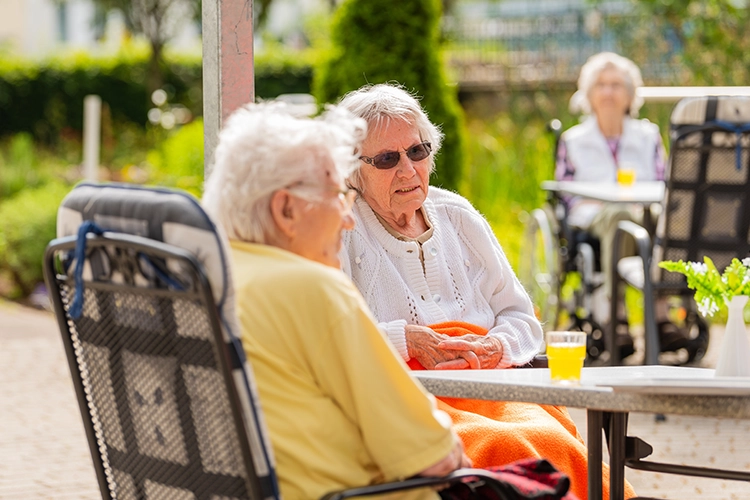 Seniorinnen sitzen im Garten an einem Tisch