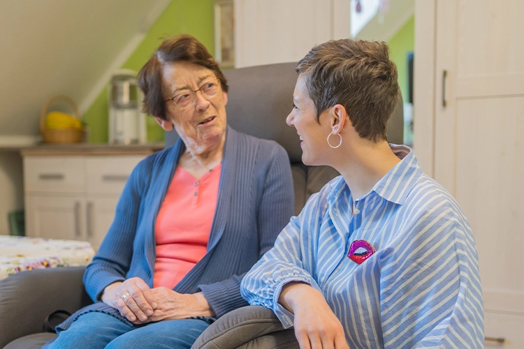 Junge Frau unterhält sich angeregt mit einer Seniorin