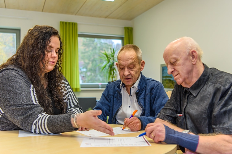 Betreuerin im Gespräch mit zwei Bewohnern