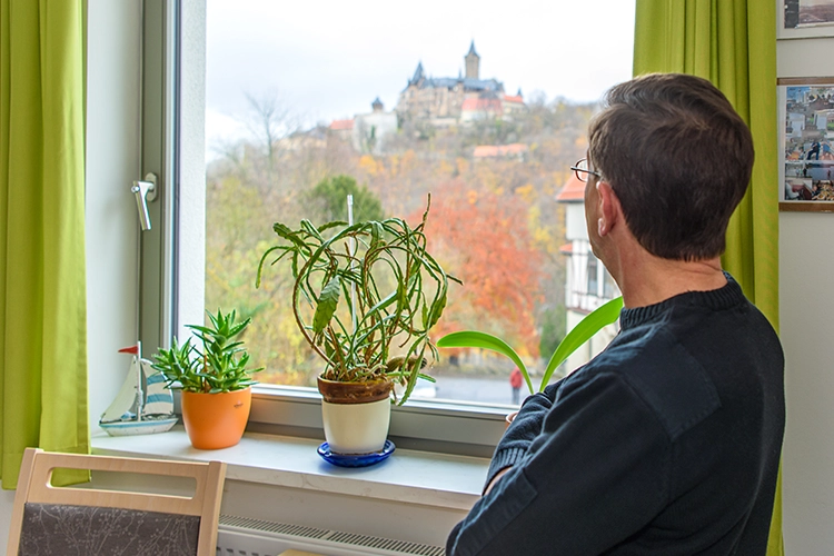 Mann schaut aus dem Fenster auf Berg mit Schloß