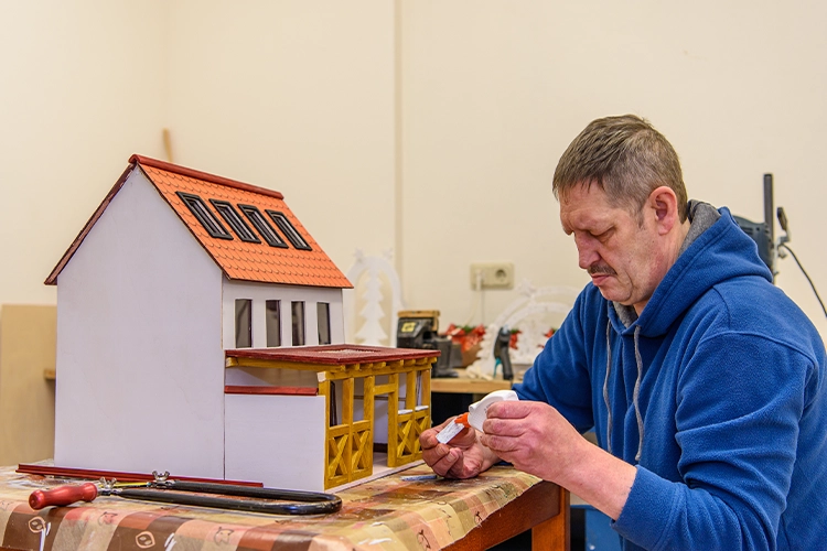 Mann arbeitet an Modellhaus im Therapieraum