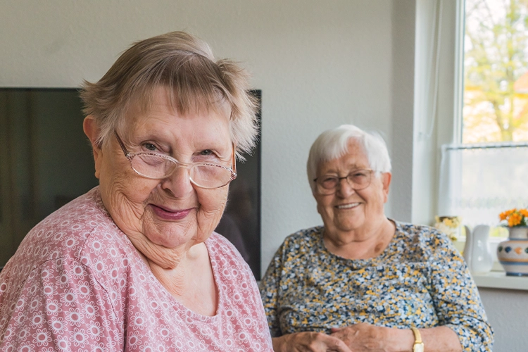 Zwei ältere Frauen sitzen gemeinsam in einem hellen Raum