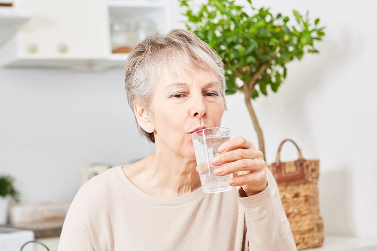 Ältere Frau trinkt Wasser aus einem Glas