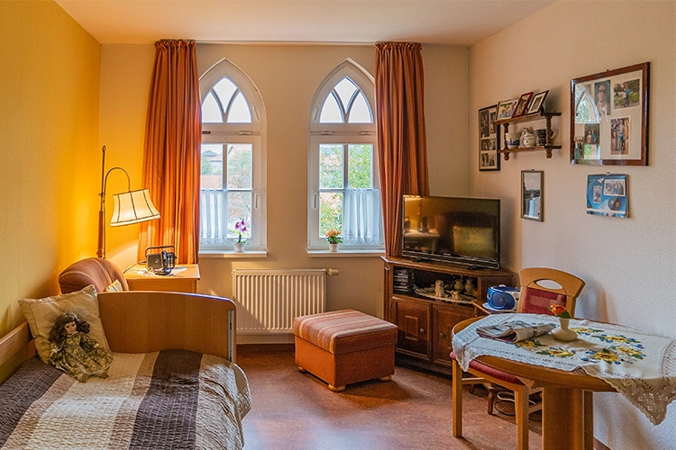 Gemütliches Bewohnerzimmer mit Bett und Sitzecke