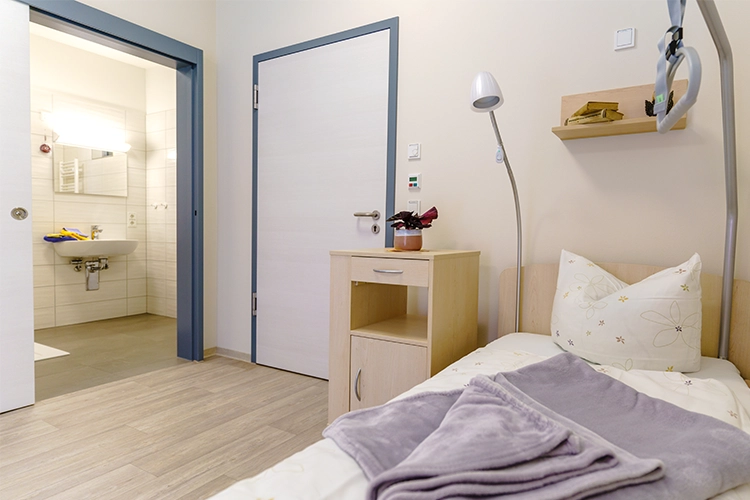 Pflegezimmer mit Bett und barrierefreiem Bad
