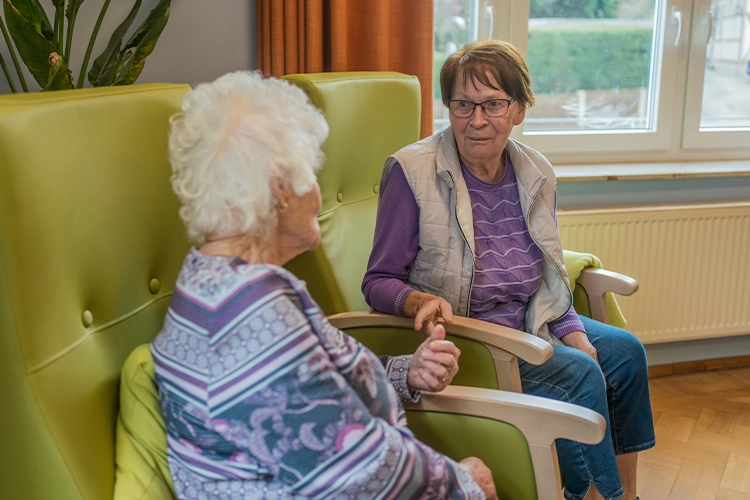 Zwei Seniorinnen im Gespräch im Aufenthaltsraum