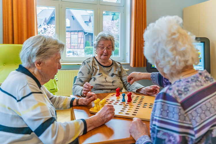 Gruppe von Seniorinnen beim Brettspiel am Tisch
