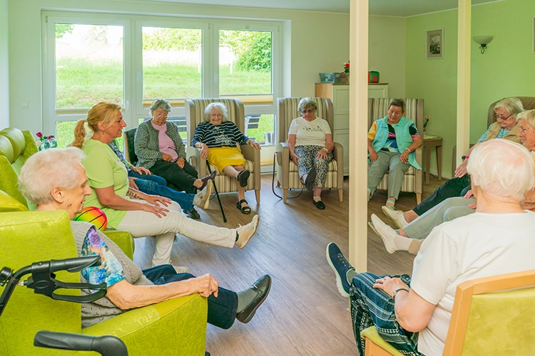 Gruppe von Seniorinnen macht gemeinsam Bewegungsübungen im Stuhlkreis