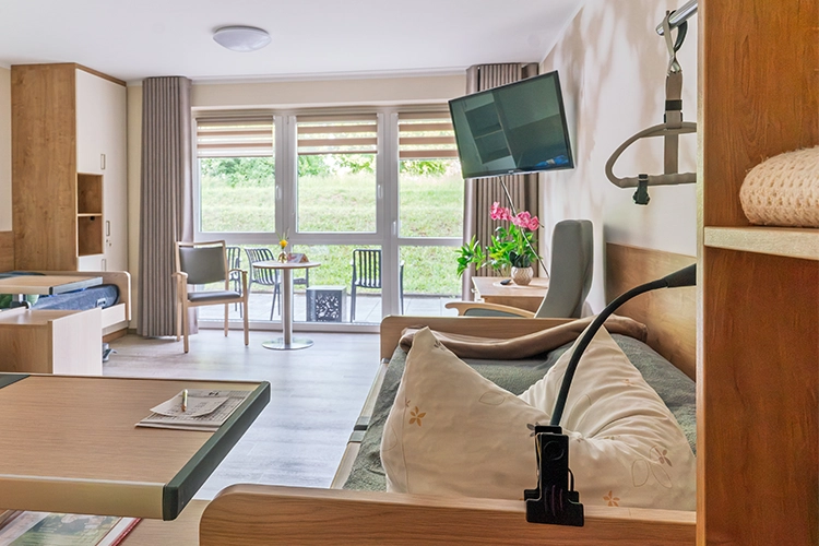 Helles modernes Doppelzimmer mit Pflegebetten, Fernseher und Terrassenzugang