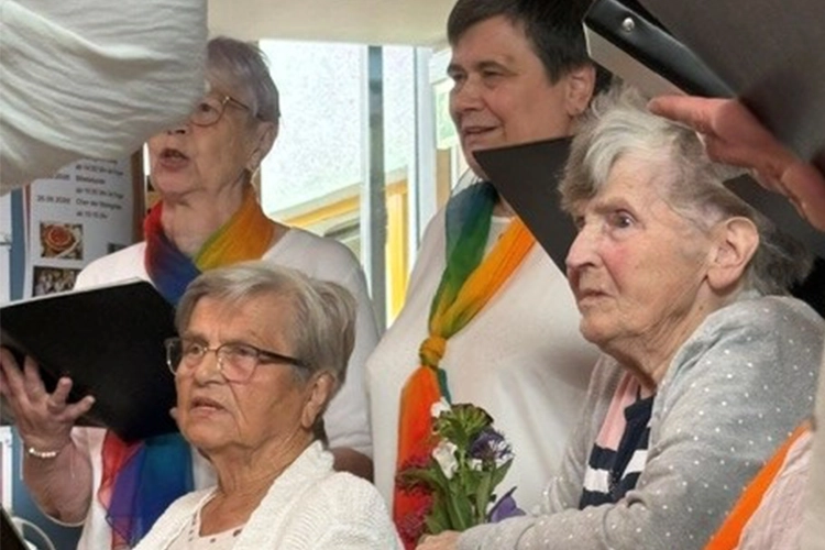 Sängerinnen und Sänger des Benzingeröder Frauenchors mit bunten Schals singen aus Notenmappen