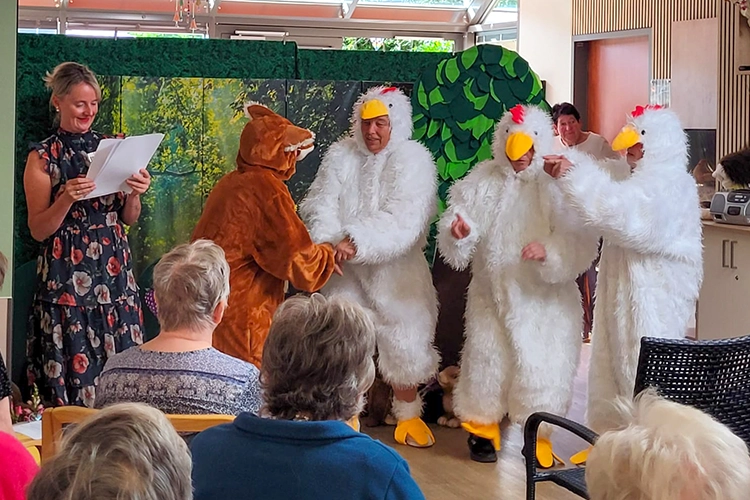 Darstellerin liest vor, Fuchs- und Hühnerkostüme agieren daneben auf der Bühne.